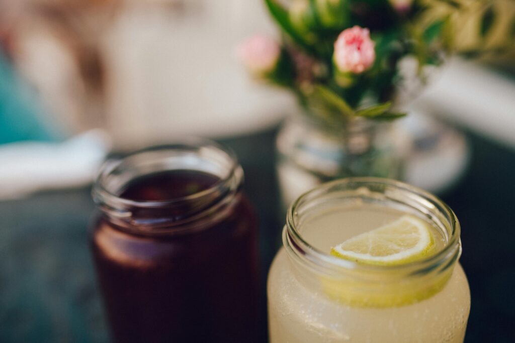 Close-up of refreshing citrus drinks in mason jars with flowers in the background.