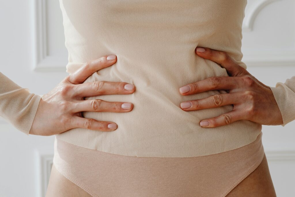 Close-up of a woman's hands resting on her waist, showcasing nude clothing.